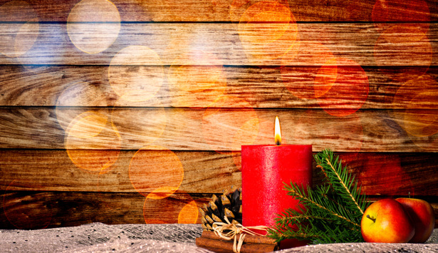 Ett rött ljus som står på ett bord bredvid ett äpple.