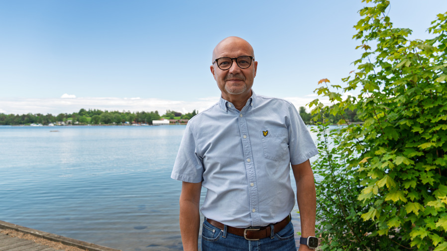 Kommunalråd Torbjörn Colling står leendes på en brygga intill ett vattendrag.
