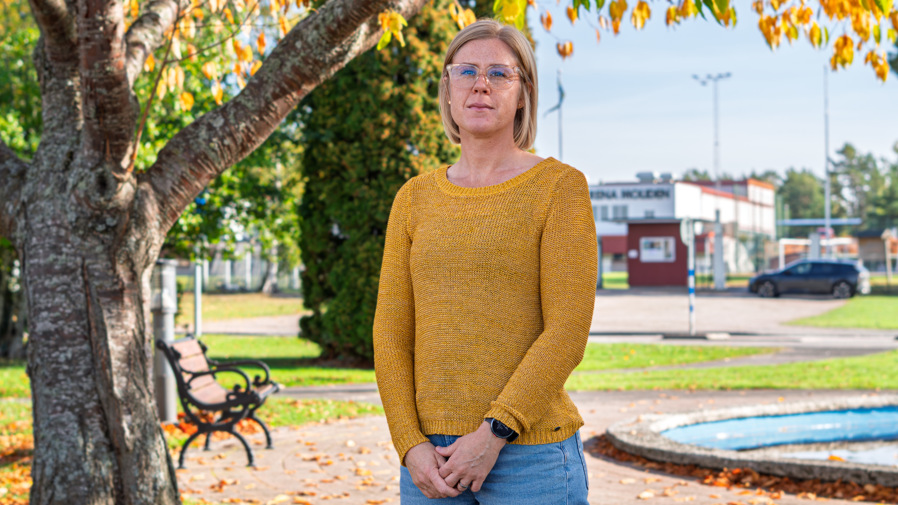 Karlsborgs kommuns folkhälsostrateg Emma Andersson tittar med en allvarsam min in i kameran. Hon står framför ett träd.