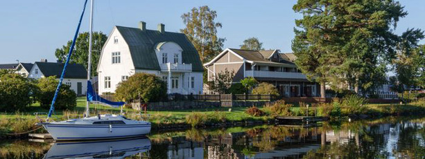 En segelbåt i Göta kanal ligger ankrad vid ett hus