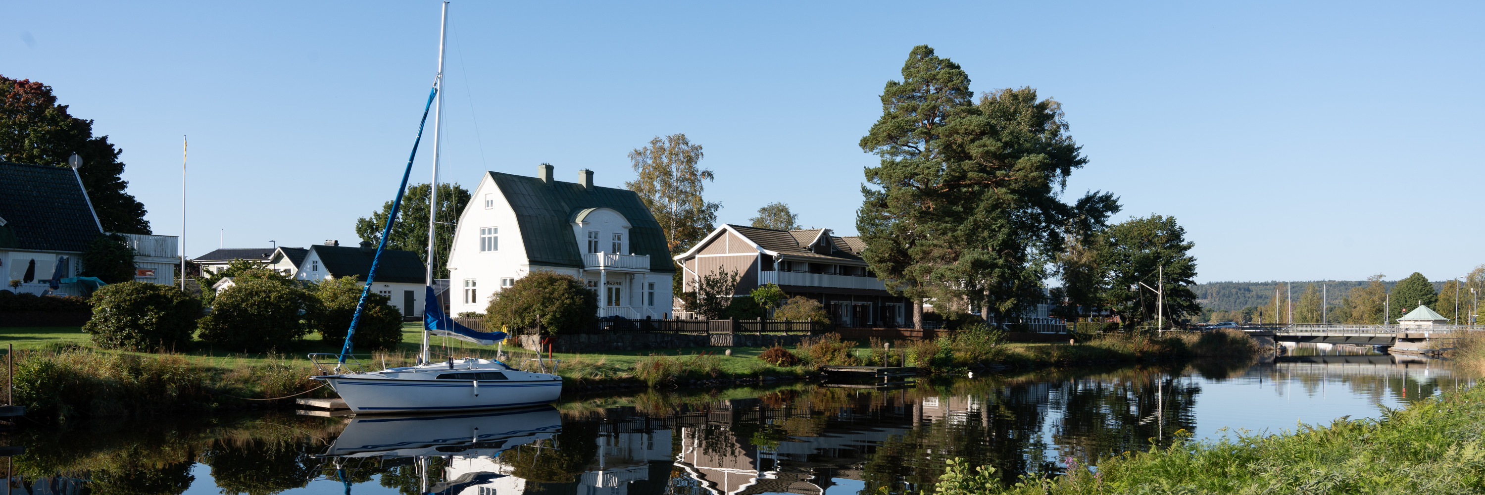 En segelbåt i Göta kanal ligger ankrad vid ett hus