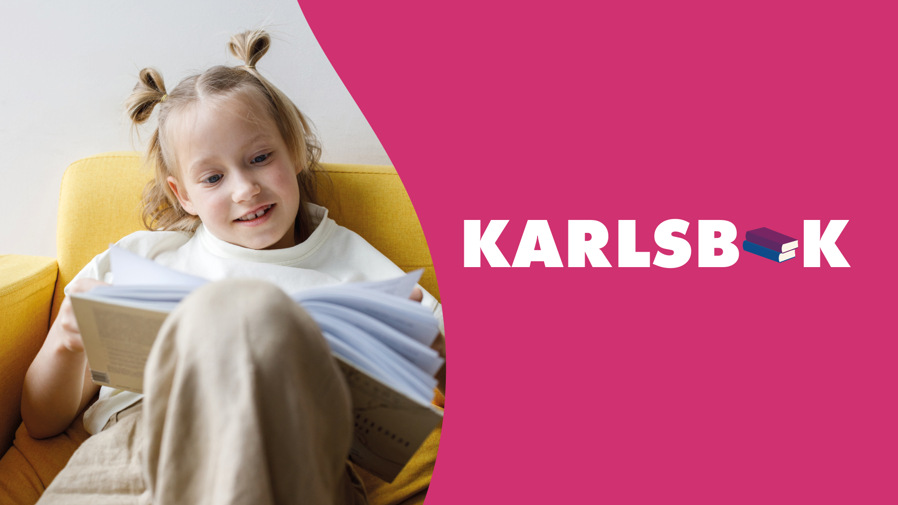 En liten flicka sitter i en soffa och läser en bok.