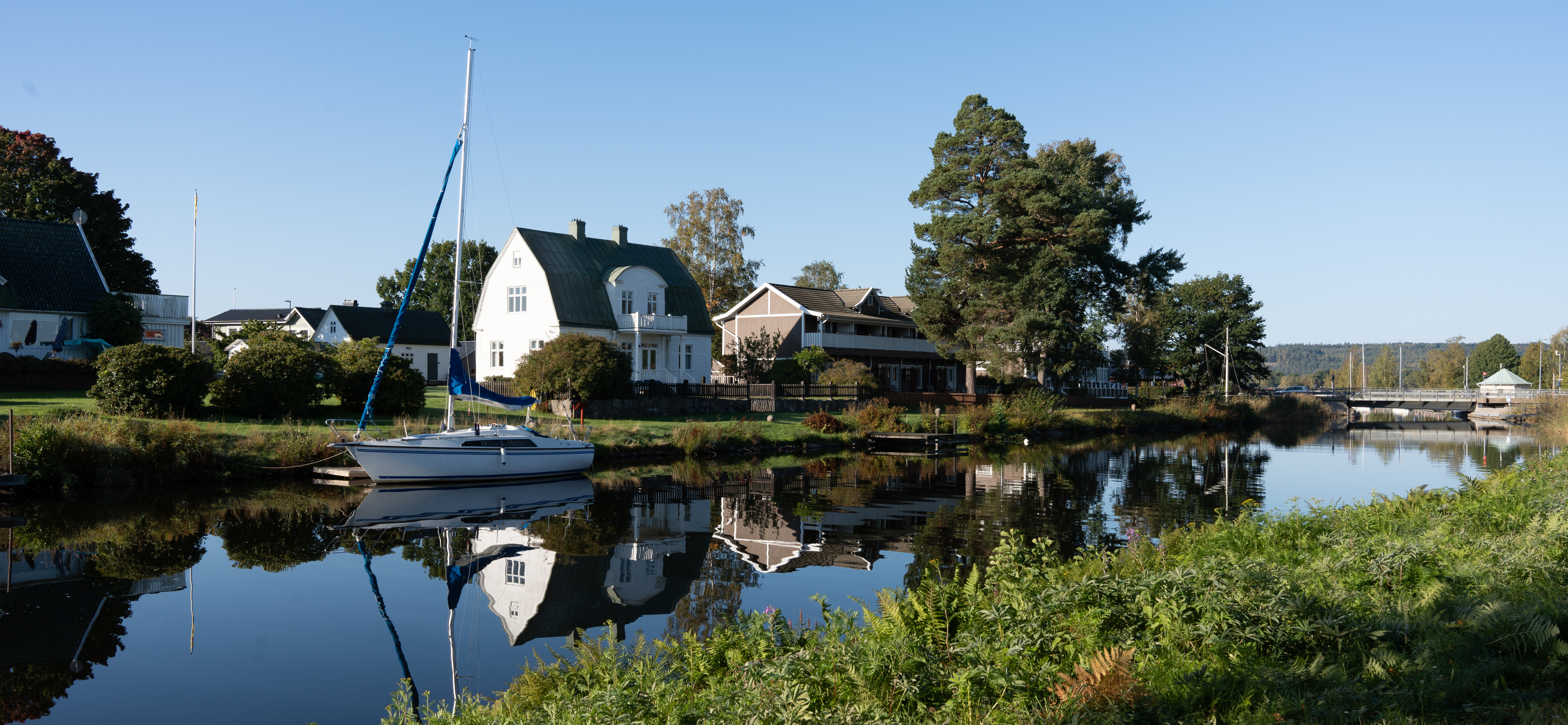 En segelbåt i Göta kanal ligger ankrad vid ett hus