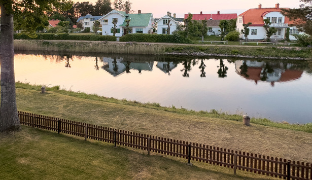 Utsikt över Göta kanal med hus i bakgrunden som speglar sig i vattnet.