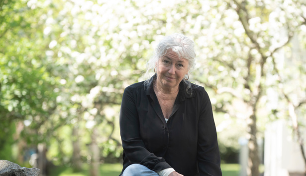 En kvinna sitter på en sten i en park.