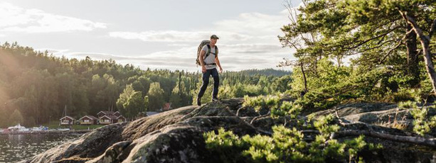 Person med packning vandrar på klippa.