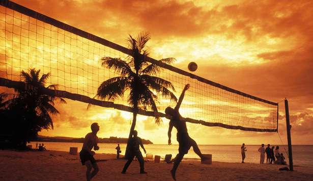 En grupp människor som spelar volleyboll på en strand.