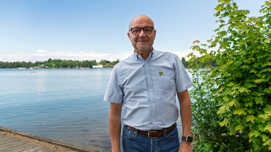 Kommunalråd Torbjörn Colling står leendes på en brygga intill ett vattendrag.