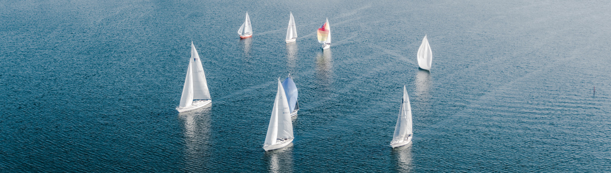 Flygbild segelbåtar på Vättern med stenbryggans båthamn i bakgrunden