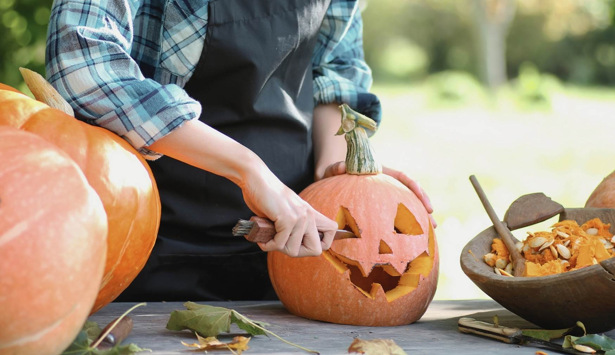 En kvinna skär upp en pumpa med en kniv.