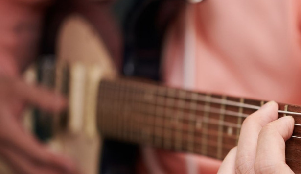 En man spelar gitarr med händerna.