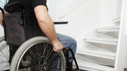 Person i rullstol framför trappa
