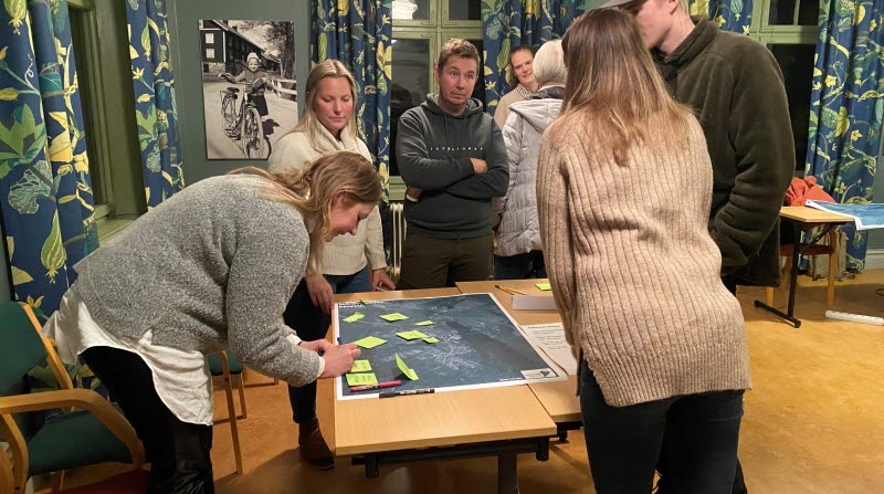 Arkitekten Linnéa Hedin pratar och tittar på kartor tillsammans med deltagare