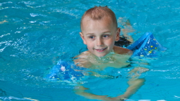 Pojke simmar med armpuffar