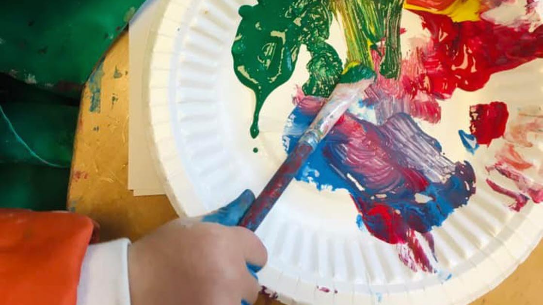 Hand från ett barn som målar med akrylfärg.