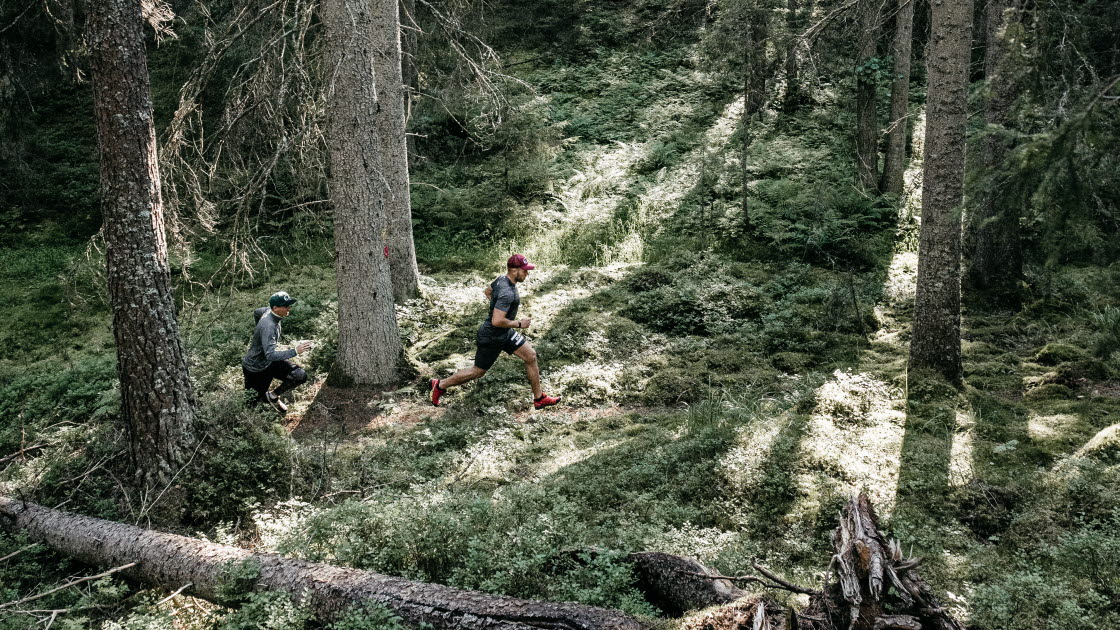 Två personer löptränar i skogen